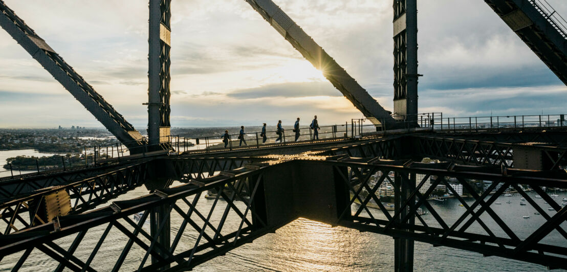 Menschen laufen über das Stahlgerüst einer Brücke