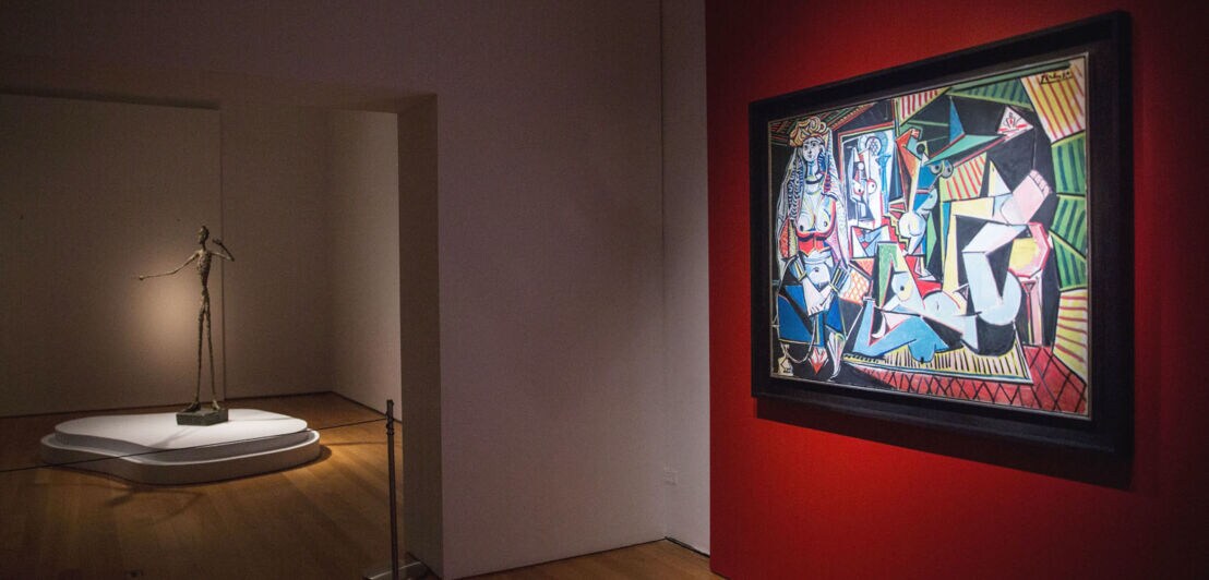 Picassos Gemälde Les Femmes d’Alger an einer roten Wand in einer Ausstellung 
