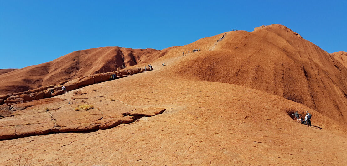 Touristen und Touristinnen auf dem roten Berg Uluru