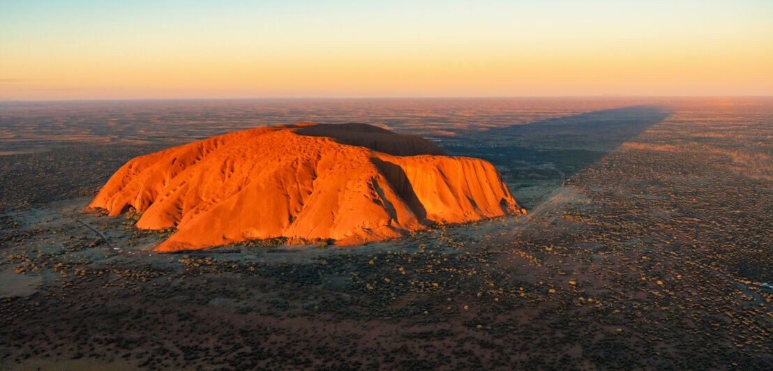 Luftaufnahme des rot leuchtenden Uluru Bergs in der Abendsonne