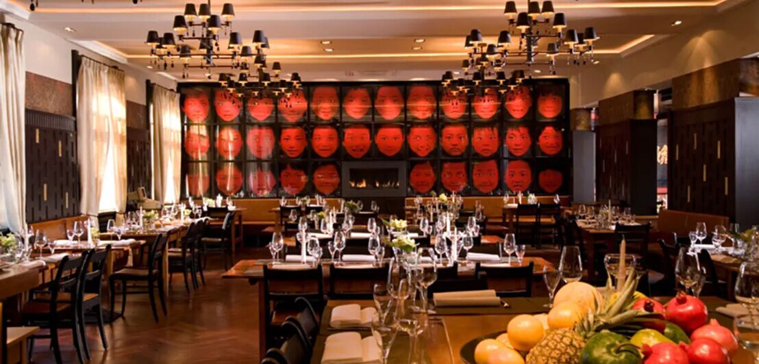 Innenraumaufnahme eines edlen, menschenleeren Restaurants mit gedeckten Tischen und asiatischen Designelementen