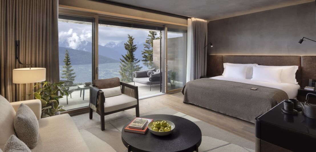 Hotelzimmer mit Designermöbeln, Panoramafenstern und Berglandschaft im Hintergrund