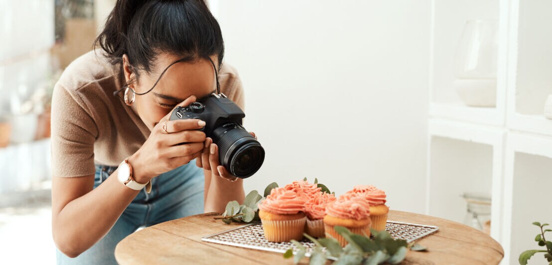 Eine junge Frau fotografiert Cupcakes