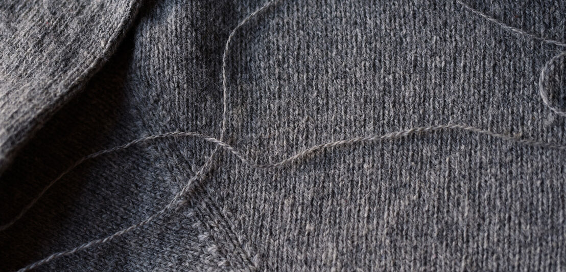 Nachaufnahme eines Strickpullovers aus Wolle in der Farbe grau.