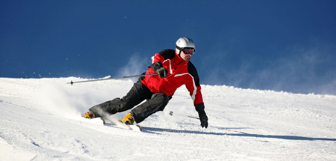 Ein Skifahrer in Kurvenlage auf einer Piste