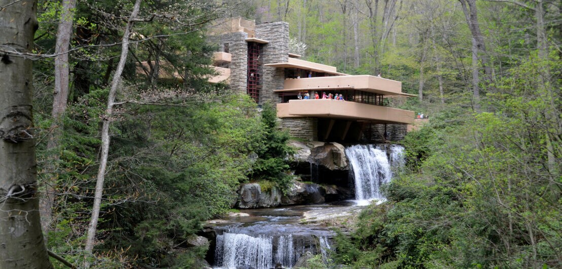 Ein Haus auf mehreren Ebenen über einem Wasserfall inmitten eines Waldes