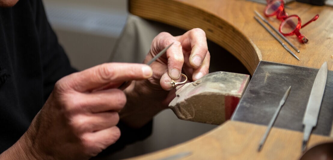 Hände einer Goldschmiedin bearbeiten einen Ring an der Werkbank von Jan Spille