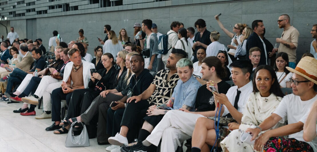 Menschen sitzen am Rande des Laufstegs einer Fashionshow