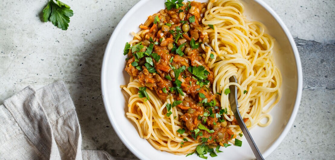 Vegetarische Linsen Bolognese-Pasta mit Petersilie in einer weißen Schale