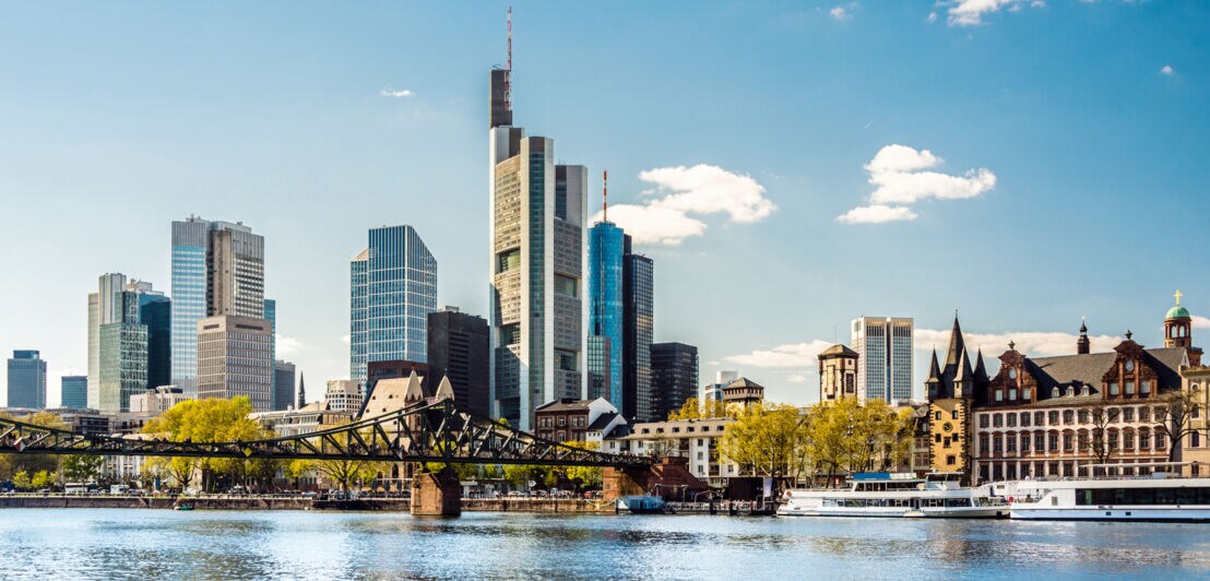 Skyline von Frankfurt am Main mit Fluss und Brücke im Vordergrund