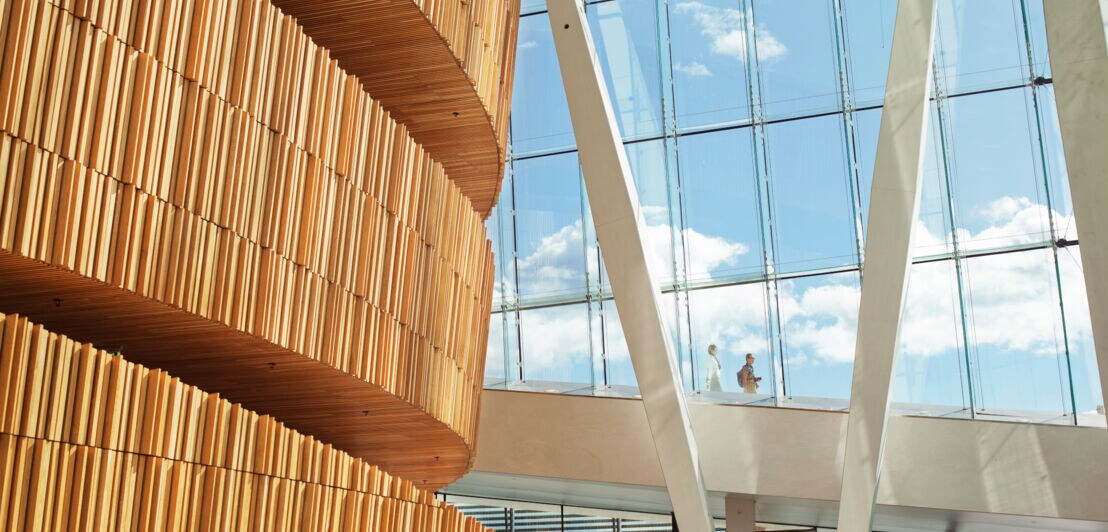 Das Innere eines modernen Gebäudes mit Holzkonstruktionen und Glasfassade mit Blick in den Himmel