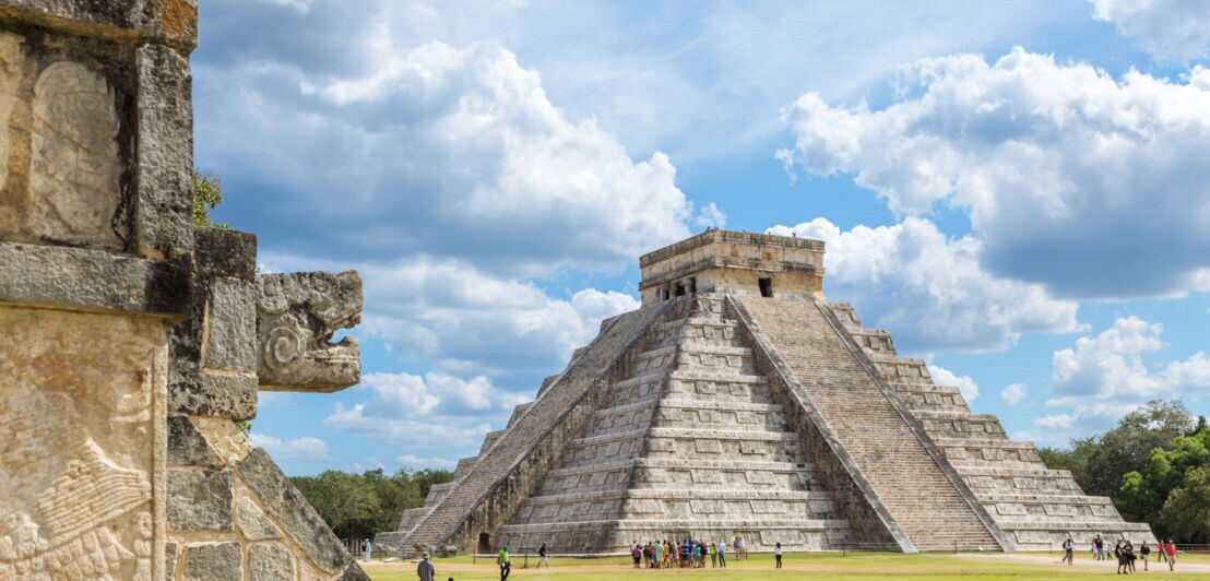 Maya-Ruinenstätte mit Besuchern an einer Treppenpyramide