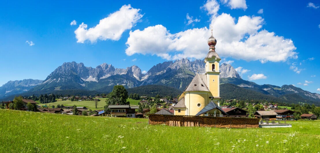 Ein Dorf mit Kirche vor einem Bergpanorama
