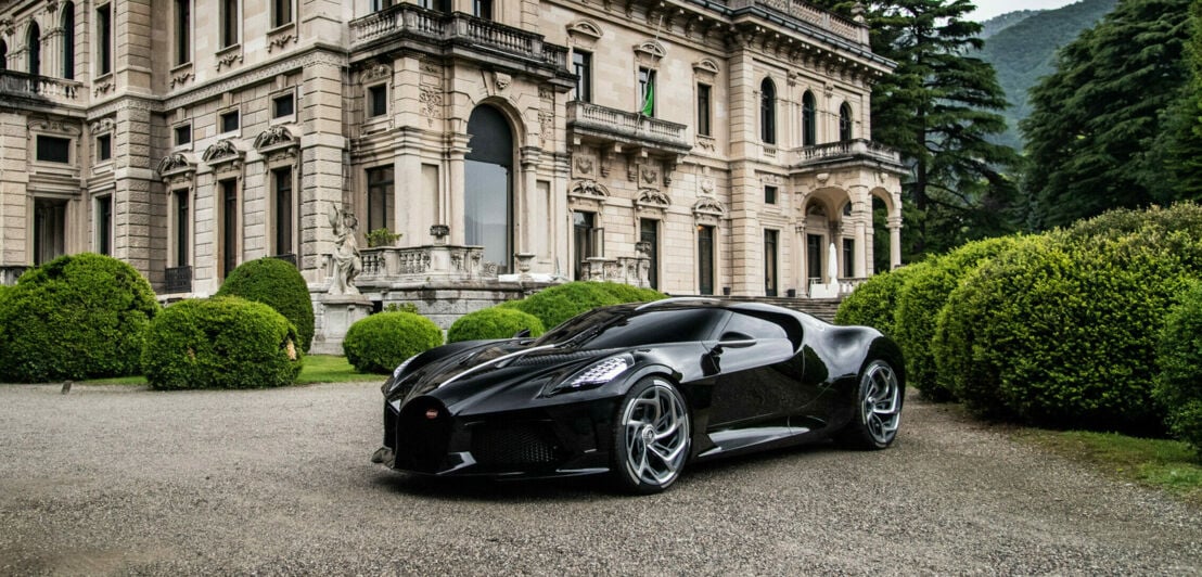 Ein schwarzer Bugatti vor einem alten Schloss.