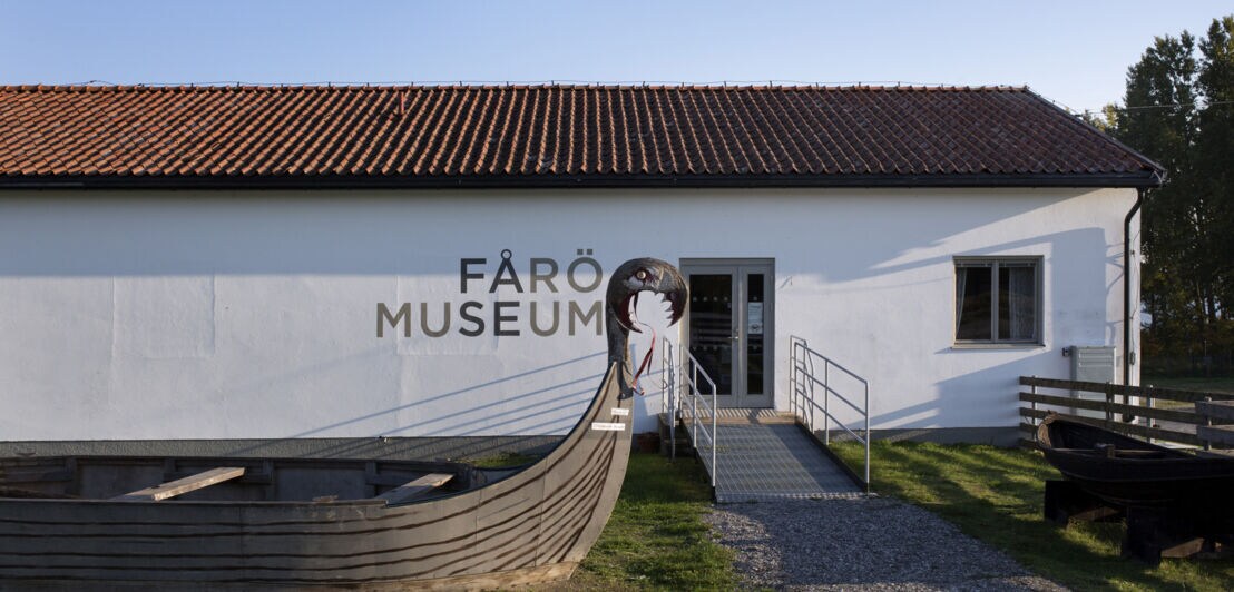 Außenansicht des Farö-Museums, vor dem ein Holzschiff steht.