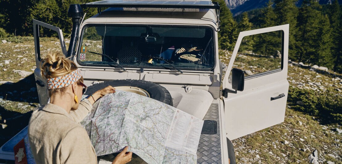 Eine Frau studiert eine Karte an ihrem Auto.