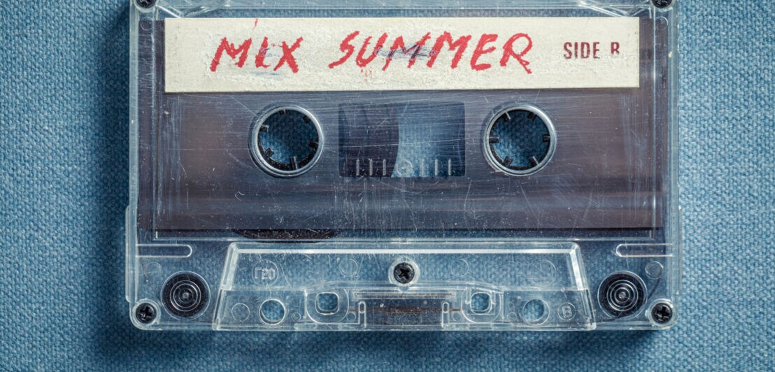 Nahaufnahme einer Kassette mit der Aufschrift „Mix Summer” auf blauem Stoff