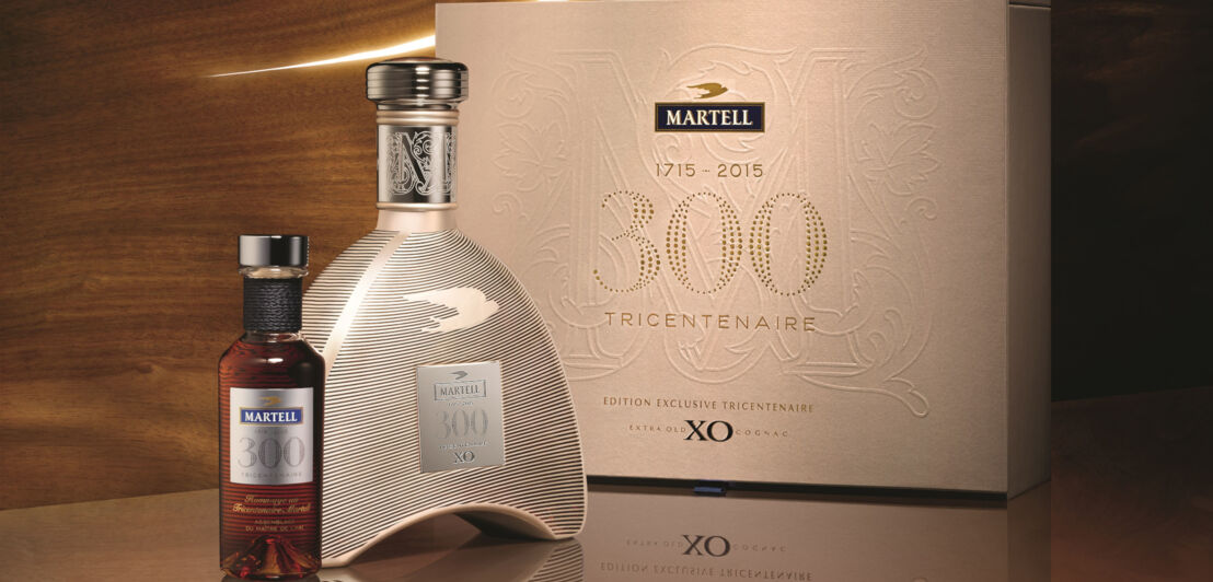 Zwei Flaschen Martell 300 Tricentenaire vor einem hellen Verpackungskarton