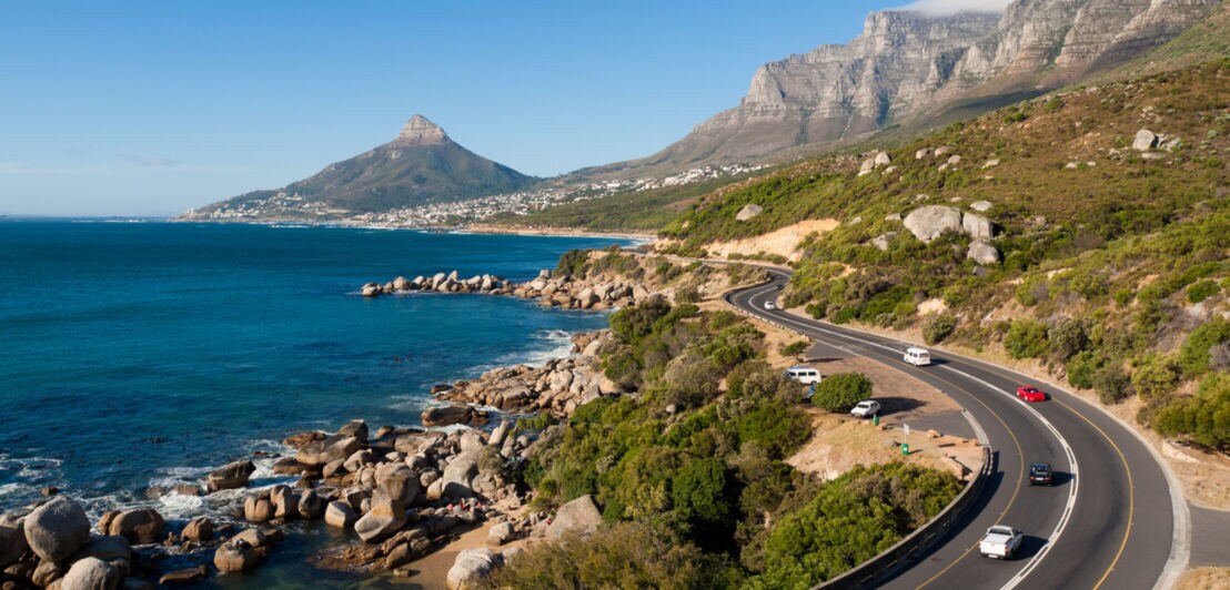 Autos fahren auf der Graden Route entlang der südafrikanischen Küste, im Hintergrund Kapstadt
