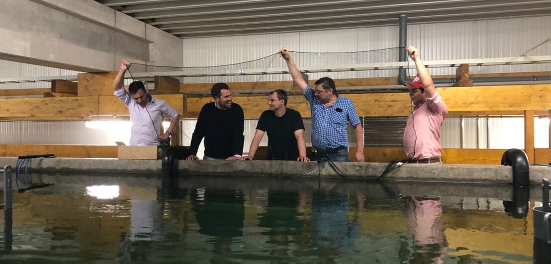 Fünf Männer stehen an einem Becken, drei von ihnen halten ein Netz in die Höhe