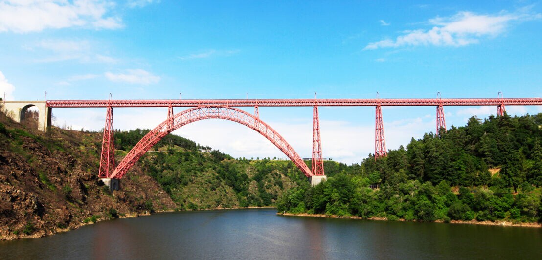 Eine rote Eisenbahnbrücke aus Stahl über einem Fluss