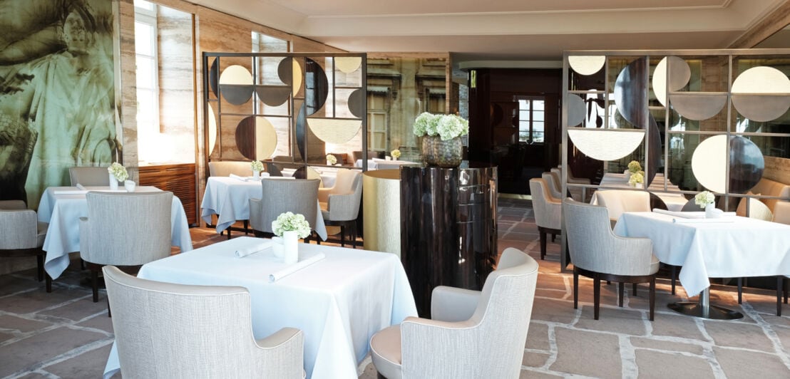 Weiß gedeckte Tische und gepolsterte Stühle im Restaurant Vendôme