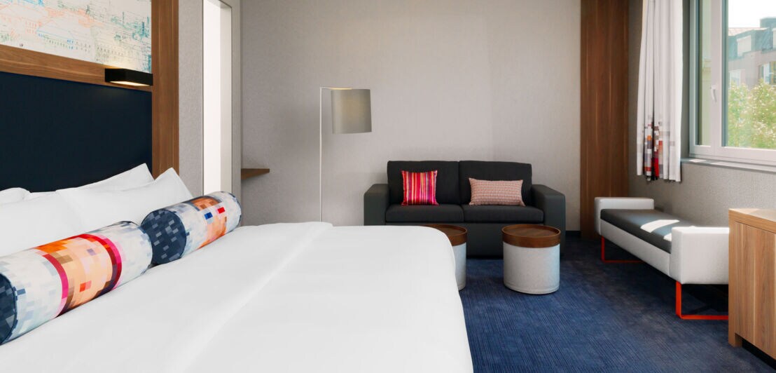 Blick in ein Hotelzimmer mit Bett und Sofamöbeln