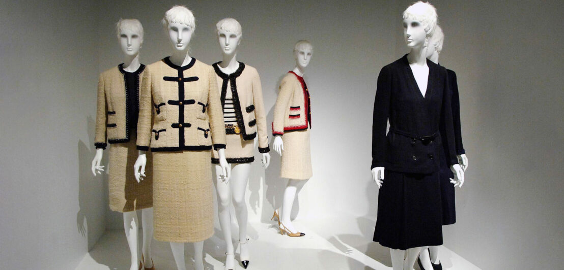Kostüme und Kleider von Chanel an weißen Schaufensterpuppen in einem Ausstellungsraum