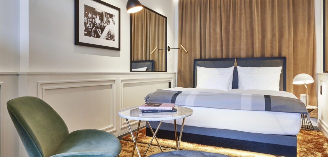 Blick in Hotelzimmer mit Doppelbett, Samtvorhängen und Samtsessel