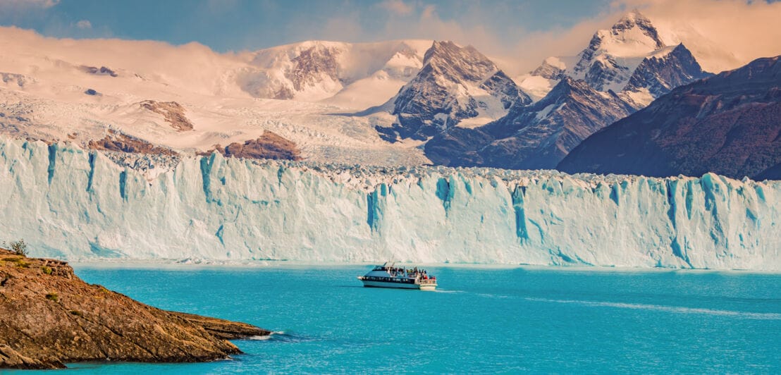 Panoramaaufnahme des Gletschers Perito Moreno mit einem Touristenboot, das durch türkisblaues Wasser fährt