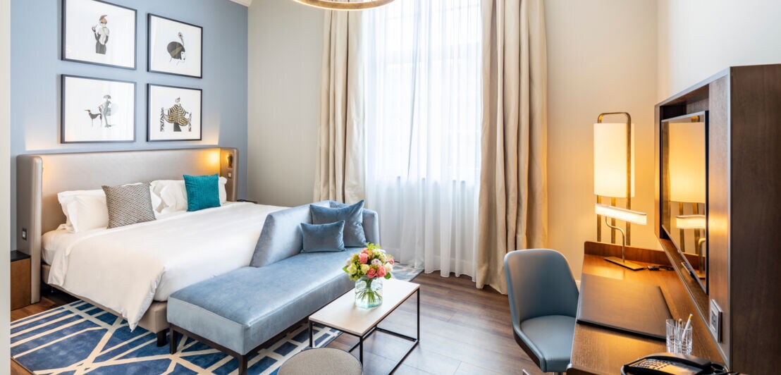 In Blautönen eingerichtetes Hotelzimmer mit Bett und Schreibtisch