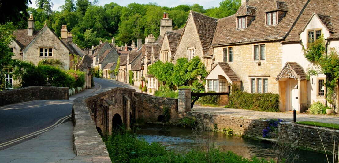 Kleines, englisches Dorf mit historischen Häusern aus Kalksandstein an einem Bachlauf