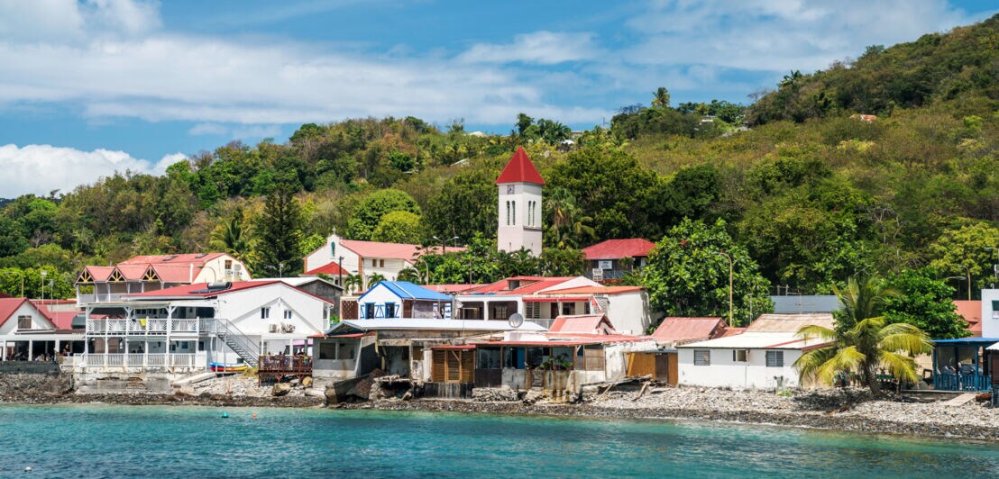 Ein kleines, karibisches Fischerdorf am Meer, umgeben von tropischer Vegetation