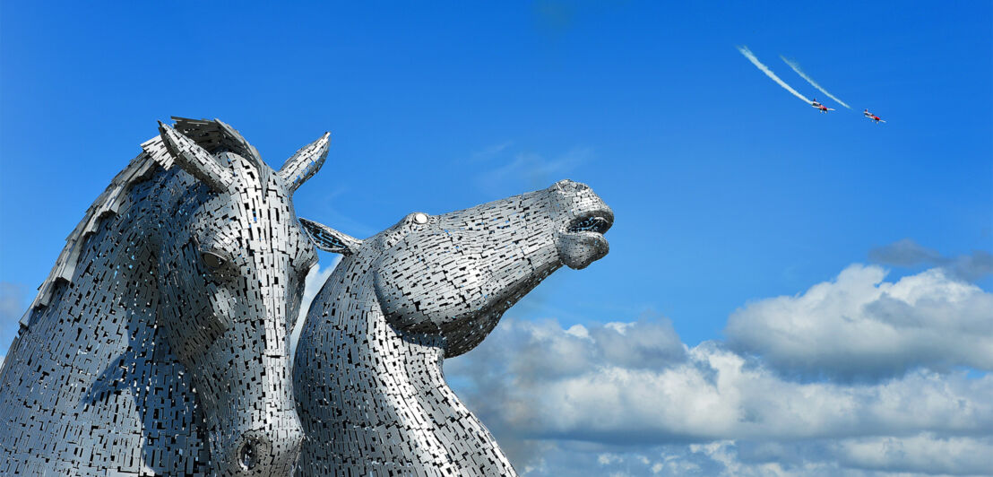 Aufnahme von zwei Pferdeköpfen aus Metall vor blauem Himmel