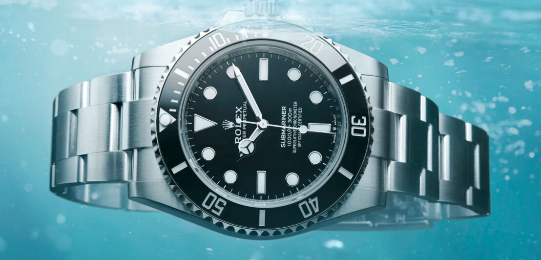 Close-up einer im Wasser schwebenden Rolex-Uhr mit schwarzem Zifferblatt und metallenem Gliederarmband