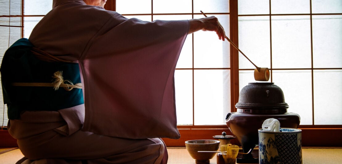 Eine Frau im Kimono bei einer traditionell japanischen Teezeremonie