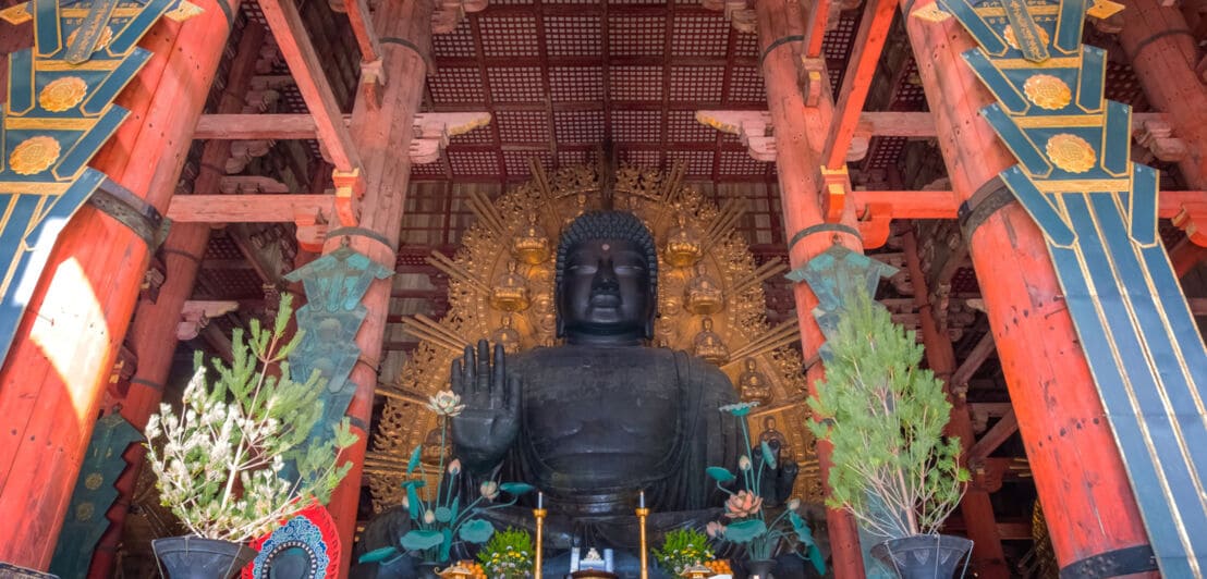 Überdimensionale bronzene Buddhastatue, davor ein Altar