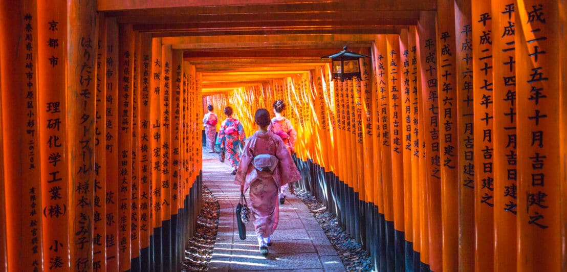 Junge japanische Mädchen im Kimono gehen durch die Tore des Fushimi-Inari-Tempels in Kyoto