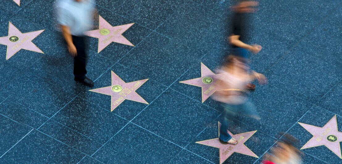 Fußgänger in der Bewegungsunschärfe laufen über die Sterne der Hollywoodstars auf dem Gehweg Walk of Fame