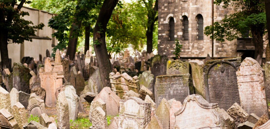 Schiefe, eng beieinanderstehende Grabsteine auf einem Stadtfriedhof