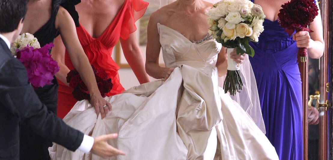 „Sex and the City“-Star Sarah Jessica Parker in einem weißen Hochzeitskleid von Vivienne Westwood, umringt von ihren Freundinnen in blauen, roten und schwarzen Kleidern