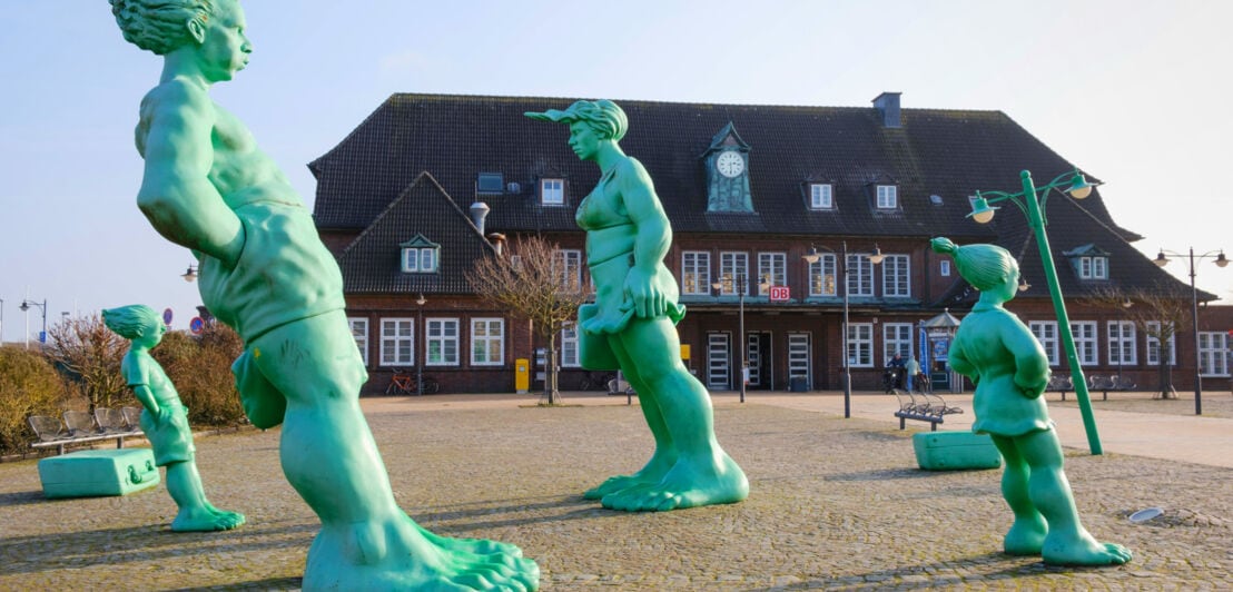 Vier grüne, übermannsgroße und schrägstehende Skulpturen auf dem Bahnhofsvorplatz in Westerland