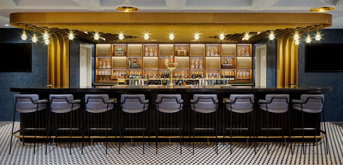 Frontale Innenraumaufnahme einer modernen, edlen Bar mit gepolsterten Barhockern