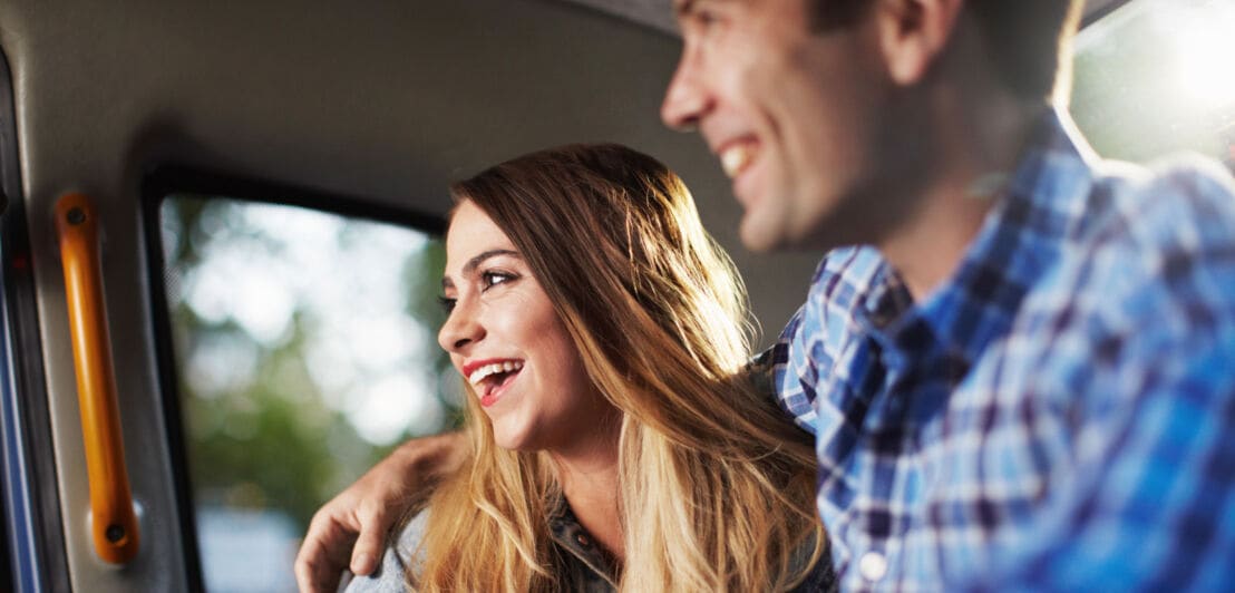 Nahaufnahme eines glücklichen, lachenden Paares auf dem Rücksitz eines Taxis