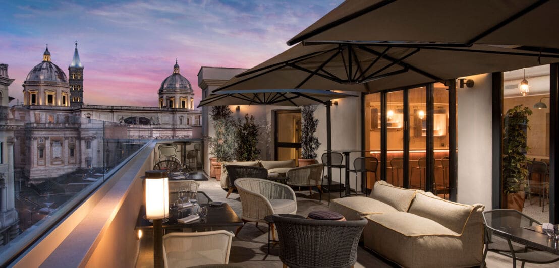 Terrasse eines modernen, eleganten Hotels mit Sitzgelegenheiten im Stadtzentrum Roms bei Abenddämmerung