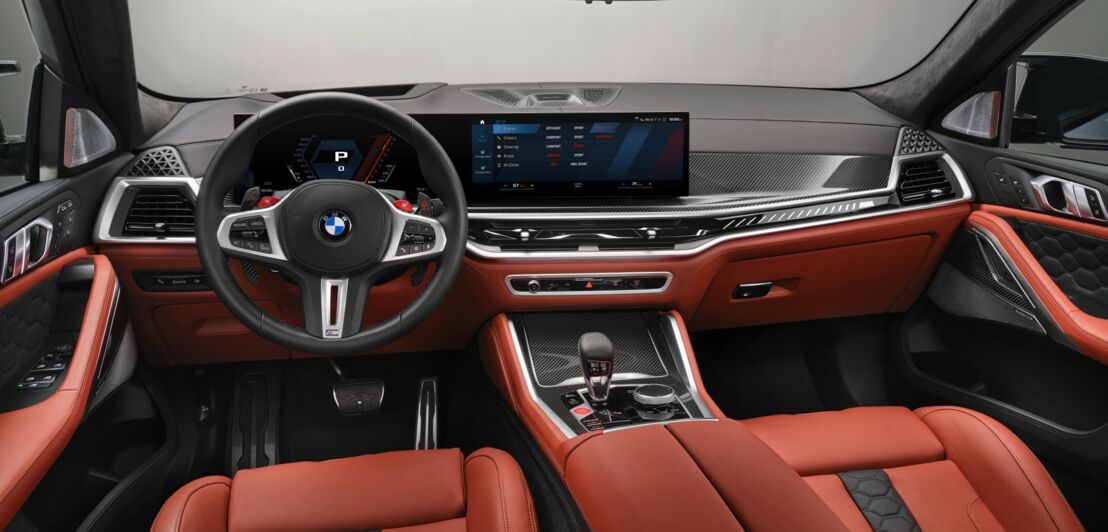 Blick aufs Armaturenbrett eines BMW mit Curved Display und Innenraum in Rot und Schwar