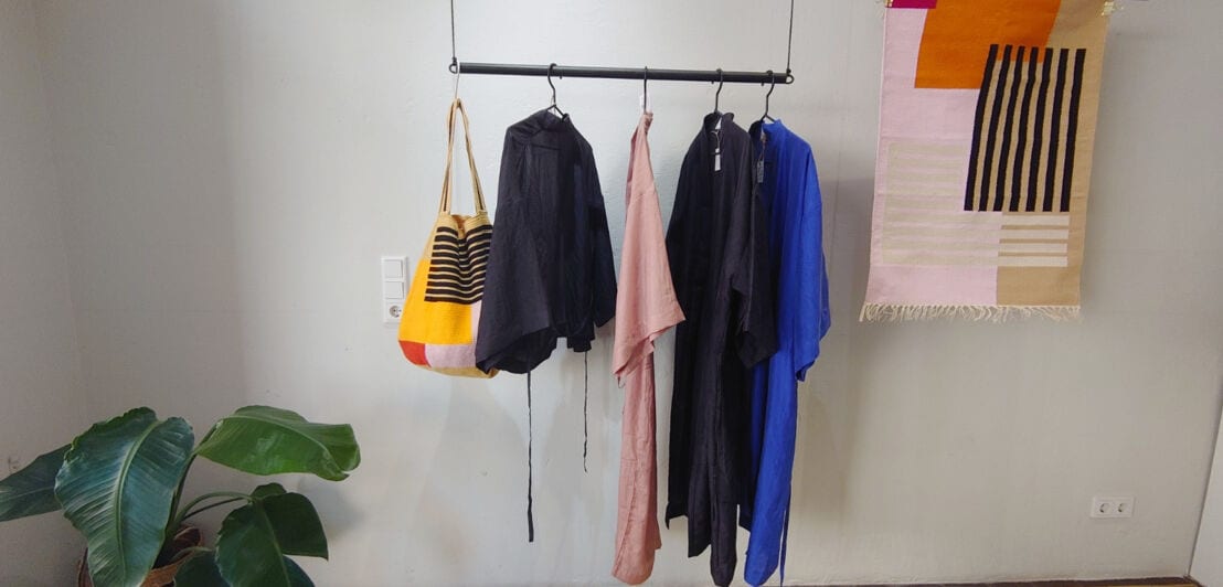 Zwei Kleiderstangen, auf denen Textilien des Labels FOLKDAYS präsentiert werden.