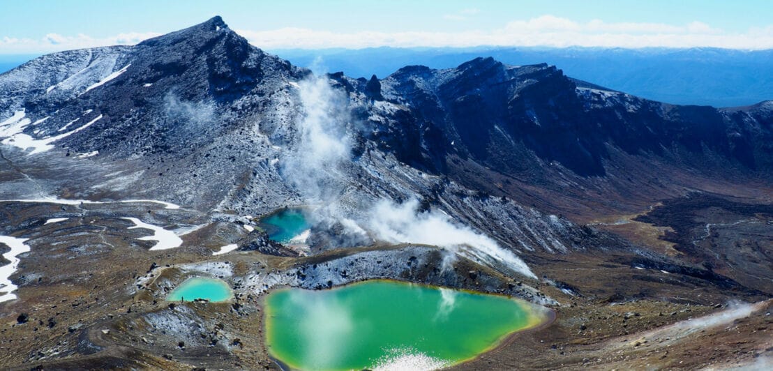 Vulkanlandschaft mit grünen Bergseen und hervorsteigendem Wasserdampfwolken