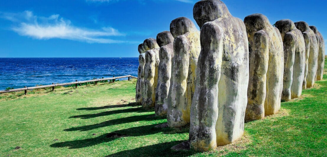 Mehrere Statuen stehen an einem Küstenabschnitt