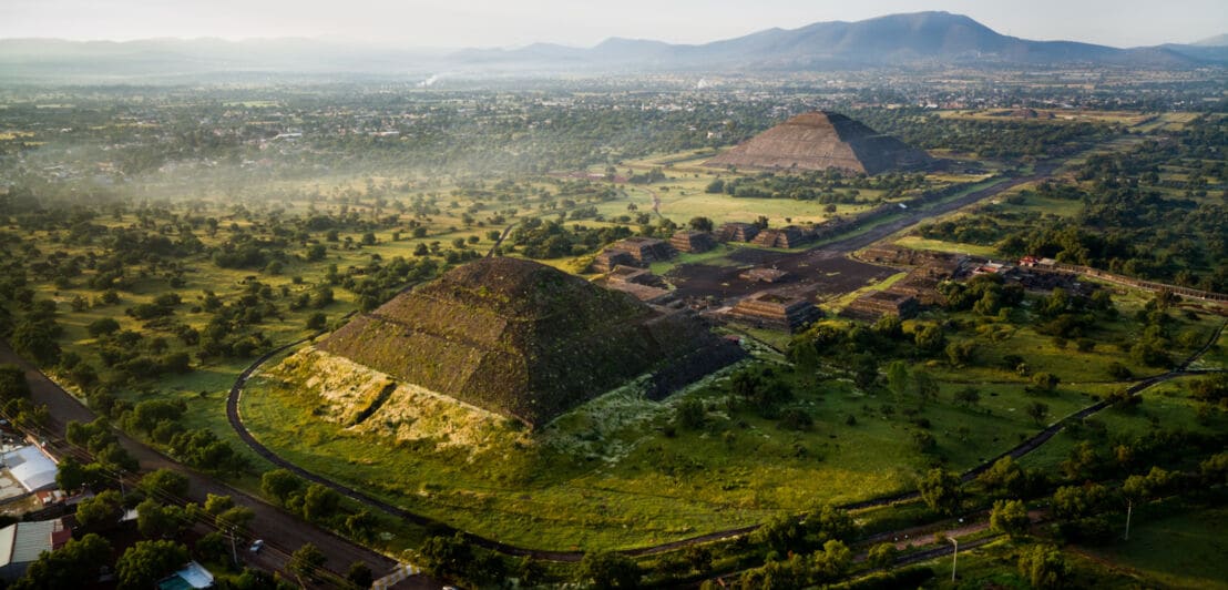 Luftaufnahme der Pyramiden von Teotihuacán, umgeben von grüner Landschaft